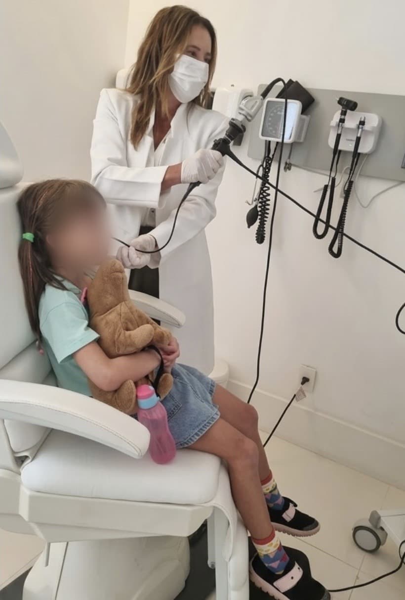 Dra. Viviane examinando o nariz de uma criança